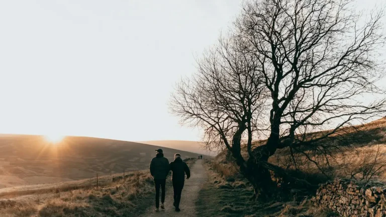 Two people walking together along a path at sunrise