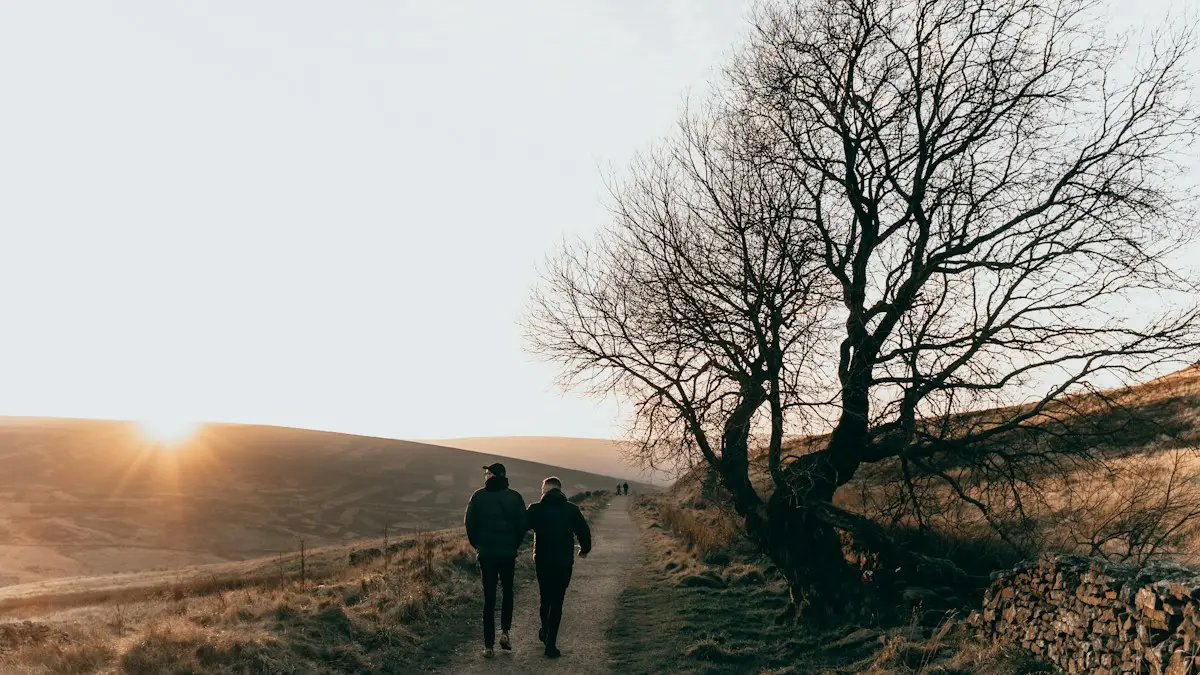 Two people walking together along a path at sunrise